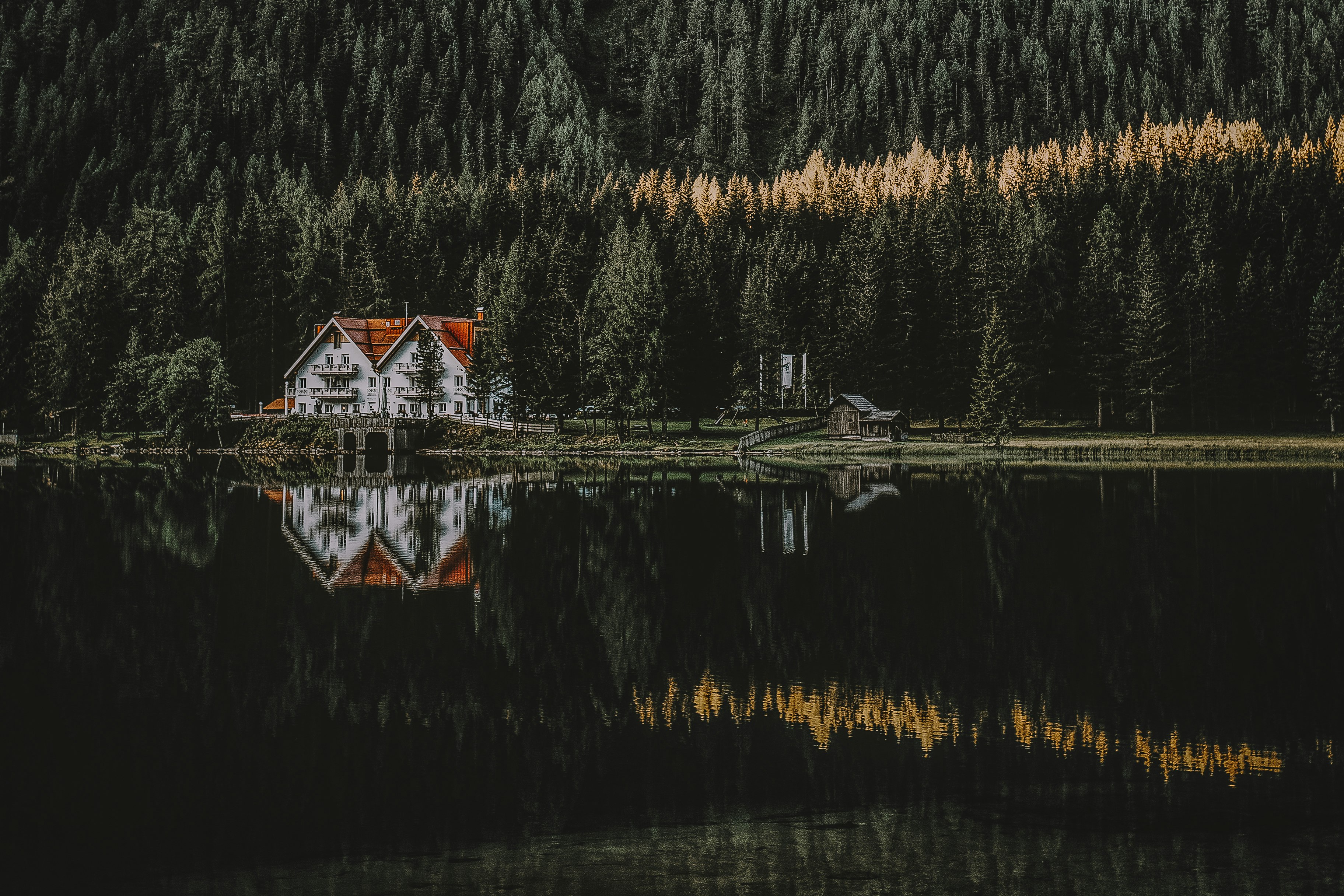 white and brown house with reflection on water surrounded with trees